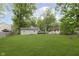 A large backyard area surrounded by large green trees, with plenty of lawn space at 5110 S State Ave, Indianapolis, IN 46227