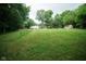 Expansive green backyard with mature trees and several outbuildings offering space and nature at 5116 W County Road 450 S, Coatesville, IN 46121