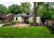 Picturesque backyard with a brick patio, well-kept lawn, mature trees, and charming landscaping at 5677 Carrollton Ave, Indianapolis, IN 46220