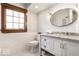 Elegant bathroom features a granite countertop, white cabinets, and a tiled floor with a framed window at 5677 Carrollton Ave, Indianapolis, IN 46220