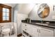 Modern bathroom boasts a stylish vanity with granite countertop and a round mirror, enhanced by the room's elegant gray walls at 5677 Carrollton Ave, Indianapolis, IN 46220