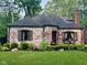 Charming brick home featuring a turret entrance, landscaped yard, and inviting curb appeal at 5677 Carrollton Ave, Indianapolis, IN 46220