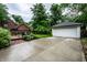 Detached garage with ample driveway space surrounded by lush landscaping and a brick patio at 5677 Carrollton Ave, Indianapolis, IN 46220