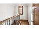 Stairwell landing featuring hardwood floors, window with wood trim and iron railing at 5677 Carrollton Ave, Indianapolis, IN 46220