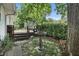 Backyard scene featuring a wooden deck, lush greenery, and a decorative bird bath at 6125 Winthrop Ave, Indianapolis, IN 46220