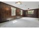 Inviting living room with wood paneling, carpeted floors, and three windows offering natural light at 6125 Winthrop Ave, Indianapolis, IN 46220