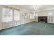 A bright living room with an ornate chandelier, green carpet and a brick fireplace in the next room at 6125 Winthrop Ave, Indianapolis, IN 46220