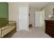 Neutral bedroom with a gold crib, dark wood dresser and white doors at 680 Albermarle Dr, Pittsboro, IN 46167