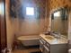 Vintage bathroom with clawfoot tub, classic wallpaper, and vanity with sink at 712 Cottage Ave, Anderson, IN 46012