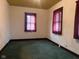 Spacious living room with green carpet features bright windows dressed with elegant maroon curtains at 712 Cottage Ave, Anderson, IN 46012