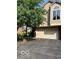 Beige two-car garage with beige siding and a large tree in front at 7707 River Rd # 10, Indianapolis, IN 46240