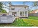 Backyard with a well-manicured lawn, gray deck with lattice, sunroom, and patio at 7766 Jamestown S S Dr, Fishers, IN 46038