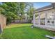 Backyard features a sunroom, deck, mature trees, green lawn and a wood fence at 7766 Jamestown S S Dr, Fishers, IN 46038
