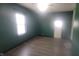 Bright living room with laminated wood flooring and emerald green accent wall at 7879 Main St, Coatesville, IN 46121