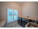 Well-lit laundry room with modern appliances, ample counter space, and a view of outdoor greenery at 8703 Gordonshire Dr, Indianapolis, IN 46278