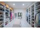 Luxurious walk-in closet with custom storage, tufted bench, and an entrance to another room at 8703 Gordonshire Dr, Indianapolis, IN 46278