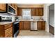 Traditional kitchen featuring wood cabinetry, tile floors and stainless steel appliances under bright lighting at 948 N Layman Ave, Indianapolis, IN 46219