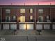 Exterior facade of a row of brick townhomes with garage and balconies and dusk sky at 11509 Reagan Dr, Fishers, IN 46038