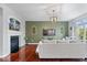 Open-concept living room featuring a fireplace, gray sofa, hardwood floors, and a green accent wall at 11509 Reagan Dr, Fishers, IN 46038