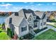 Aerial view of a beautiful two-story home with a three car garage on a well-manicured lawn near a lake at 13613 Lake Ridge Ln, McCordsville, IN 46055