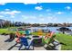 Scenic backyard featuring a lakeside fire pit and colorful Adirondack chairs at 13613 Lake Ridge Ln, McCordsville, IN 46055
