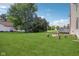 Large backyard featuring a lush lawn, a wooden deck, and a cozy fire pit area with tree stump seating at 13938 Charleswood Ct, Fishers, IN 46038
