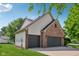 Side view of a three-car garage with brick and siding exterior and a well-maintained lawn at 13938 Charleswood Ct, Fishers, IN 46038