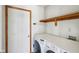 Laundry room with modern washing machine and dryer, storage shelf, and a door at 13938 Charleswood Ct, Fishers, IN 46038