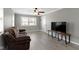 Living room with laminate flooring, neutral walls, ceiling fan, front door, and a large TV at 141 S 9Th Ave, Beech Grove, IN 46107