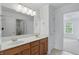 Bathroom with double sinks, wood cabinetry, and a view to the connected bedroom at 16802 Oak Manor Dr, Westfield, IN 46074