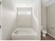 Elegant white soaking tub with a window above, next to a toilet and white walls at 1829 Archbury Dr, Avon, IN 46123