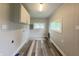 Bright laundry room with wood flooring, white cabinets, and two windows at 204 S Conger St, Saint Paul, IN 47272