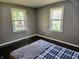 Bedroom featuring two windows and a bed with gray and plaid bedding on dark hardwood floors at 2041 Mckinley Ave, Columbus, IN 47201