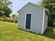 Gray vinyl-sided storage shed with a black door and a green, well-maintained lawn surrounding it at 2041 Mckinley Ave, Columbus, IN 47201