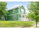 Inviting two-story home showcasing green siding, a covered front porch, and a well-manicured lawn at 2427 N Rural St, Indianapolis, IN 46218