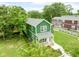 An aerial shot features a charming green home with a welcoming front porch and neatly landscaped yard at 2427 N Rural St, Indianapolis, IN 46218
