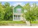 Charming two-story home featuring a green exterior, white trim, and a welcoming front porch at 2427 N Rural St, Indianapolis, IN 46218