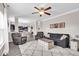 Open-concept living room with gray furnishings, a ceiling fan, and views into the dining area and a modern kitchen at 2434 Burgundy Way, Plainfield, IN 46168