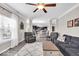 Bright living room with open layout, ceiling fan, large window, gray sofa, and access to the dining area and modern kitchen at 2434 Burgundy Way, Plainfield, IN 46168