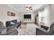 Comfortable living room with a gray sofa, armchair, ceiling fan, and a large window allowing natural light to brighten the space at 2434 Burgundy Way, Plainfield, IN 46168