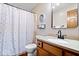 Bathroom featuring a shower-tub combo, wood vanity, and stylish decorative mirror at 2818 Locust Dr, Indianapolis, IN 46227