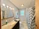 Well-lit bathroom featuring a granite countertop, sink, mirrored cabinet, modern shower curtain, and a window at 2833 Desoto Way, Columbus, IN 47203