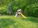 Backyard includes a custom play structure, a mature tree, and a lush lawn at 312 Hawthorne Dr, Pittsboro, IN 46167