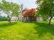 Beautiful backyard with mature trees, a patio set, and a brick home exterior at 312 Hawthorne Dr, Pittsboro, IN 46167