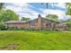 Back exterior view of a brick home featuring a wooden deck and large, grassy yard at 407 Woodland E Dr, Greenfield, IN 46140