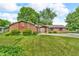 Charming single story brick home with a well-manicured lawn, mature trees, and an inviting facade at 407 Woodland E Dr, Greenfield, IN 46140