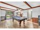 Well-lit game room with ping pong table, wood beams, sliding glass doors to a deck, and access to the kitchen at 407 Woodland E Dr, Greenfield, IN 46140