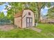 Tan shed with painted blue trim in a backyard setting with grass and trees at 407 Woodland E Dr, Greenfield, IN 46140