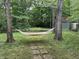 Relaxing backyard featuring a colorful hammock strung between trees, with stepping stones and a shed in the background at 5010 Melbourne Rd, Indianapolis, IN 46228