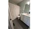 A bathroom showcasing the single sink vanity, hexagon tile floors and a shower with curtain at 5010 Melbourne Rd, Indianapolis, IN 46228